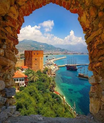 Alanya harbor viewed through a historic stone arch at Alanya Castle