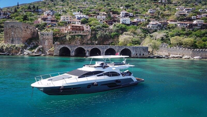 Private yacht cruising beside Alanya's historic harbor walls